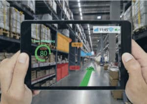 Person holding a tablet displaying augmented reality navigation inside a warehouse
